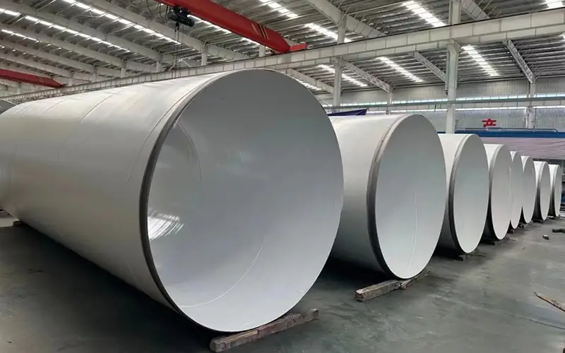 Several large-diameter steel pipes with a white 3LPP anti-corrosion coating, manufactured for a high-sulfur gas field project, inside a production facility-banner