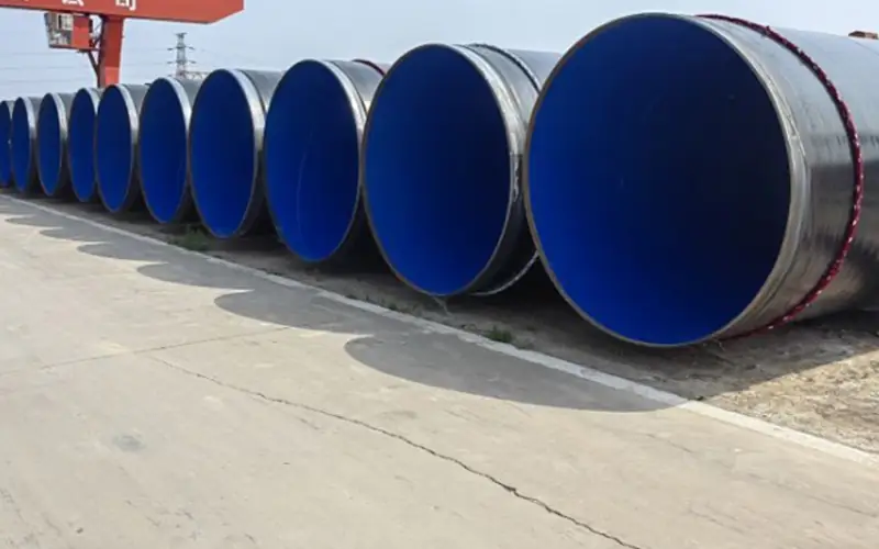 A long row of large-diameter steel pipes with a black FBE external coating and a blue internal lining, ready for an industrial project.-banner