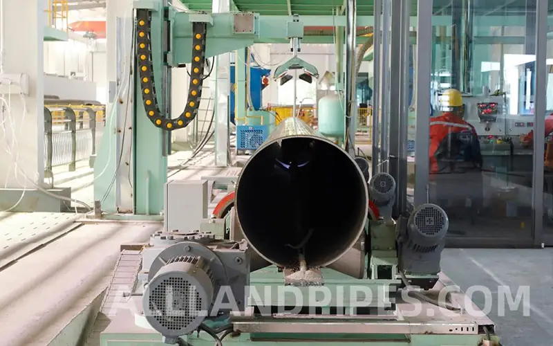 A large-diameter LSAW pipe on an automated production line in a factory, positioned for inspection of its internal weld seam.-banner