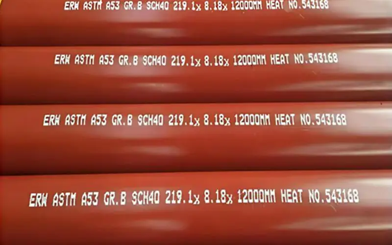 Stack of red Schedule 40 fire sprinkler pipes with their ASTM A53 Grade B specification markings clearly stenciled on the side.-banner