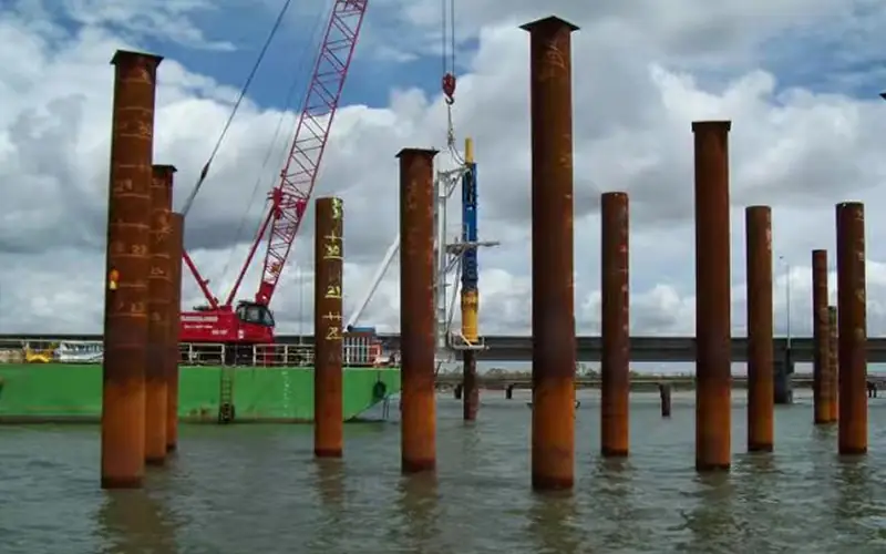 Installation of large-diameter SSAW steel pipe piles for marine bridge foundation, showing visible spiral weld seams.-banner