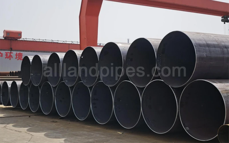 Large-diameter LSAW pipes made of various mild steel grades, including ASTM A36 and API 5L B, stacked in an outdoor storage yard for industrial infrastructure projects-banner