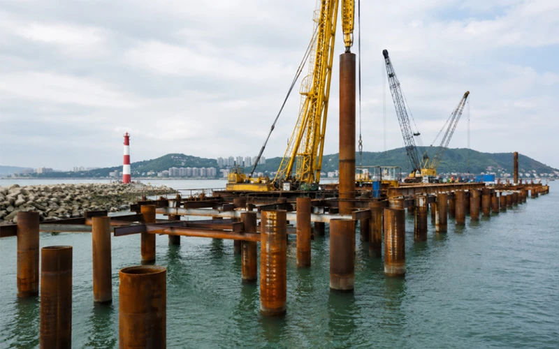 Heavy-duty steel pipe piles installed at a coastal port for flood-resistant offshore foundation support under marine conditions banner