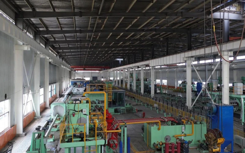 An interior view of a modern, large-scale steel pipe manufacturing workshop and automated production line equipment - Allland Pipes banner