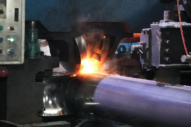 High frequency resistance welding (HFW) machine squeezing steel strip edges into a continuous longitudinal seam during ERW pipe manufacturing