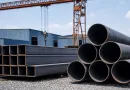 ASTM A500 Grade B structural hollow sections and ASTM A53 Grade B steel pipes stacked in an industrial yard, illustrating the difference between structural HSS and pressure pipe applications banner