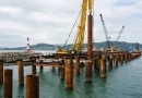 Heavy-duty steel pipe piles installed at a coastal port for flood-resistant offshore foundation support under marine conditions banner