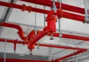Commercial fire sprinkler piping system with grooved steel pipe fittings and welded connections installed on an industrial building ceiling banner