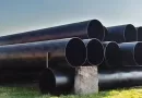 Large diameter heavy wall LSAW steel pipes with black anti-corrosion coating stacked in storage yard, ready for mining slurry pipeline projects.