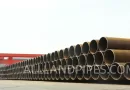 Large-diameter LSAW steel pipes neatly stacked in an outdoor storage yard before shipment. banner