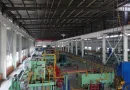 An interior view of a modern, large-scale steel pipe manufacturing workshop and automated production line equipment - Allland Pipes banner